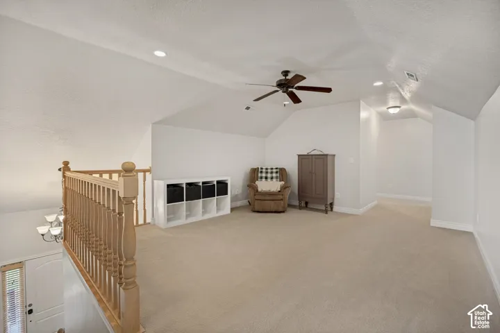 Open loft area featuring vaulted ceilings, neutral carpet flooring, recessed lighting, and a wooden handrail with balusters