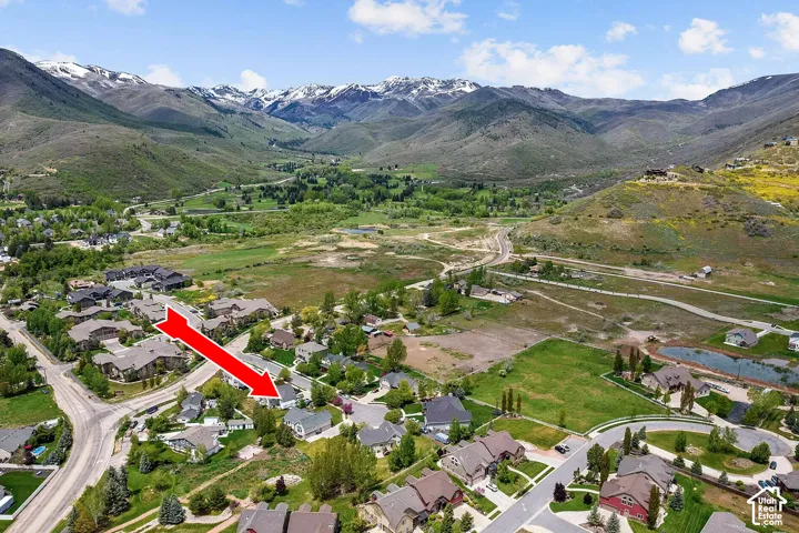 Aerial perspective of the property featuring a suburban lot, paved street access, and a prominent mountain range backdrop