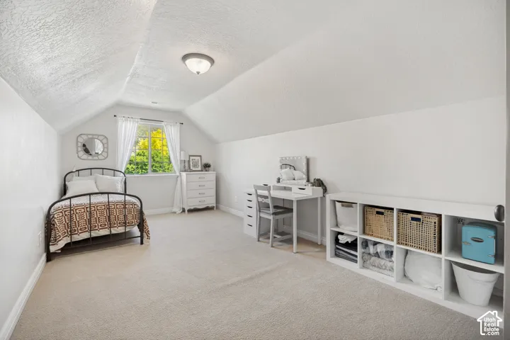 Finished space with neutral carpeting, sloped ceiling, single-pane window, and flush-mount lighting