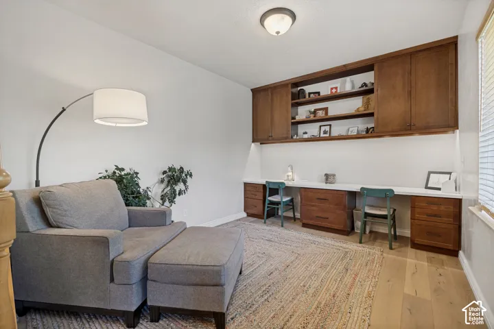 Built-in stained wood cabinetry with open shelving, solid-surface desk workspace, and wood-finish flooring