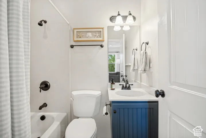 Bathroom featuring a blue beadboard vanity with a white countertop, oval undermount sink, matte black hardware, and a tub-shower combination with matching matte black fixtures