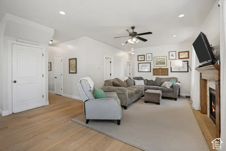 Living room featuring wood-finish flooring, a fireplace with a wood mantel and tile surround, recessed lighting, and a ceiling fan
