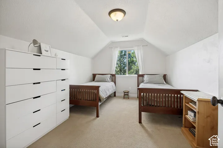 Vaulted ceilings, neutral carpeting, and a centrally located window