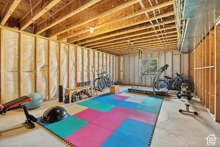 Unfinished basement space featuring exposed joist ceilings, concrete flooring, and insulated wall framing