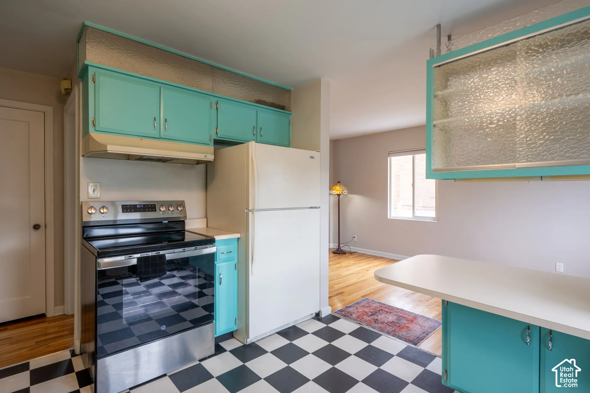 Kitchen featuring custom cabinetry with textured glass inserts, a stainless steel range, a peninsula, and a black-and-white checkered floor
