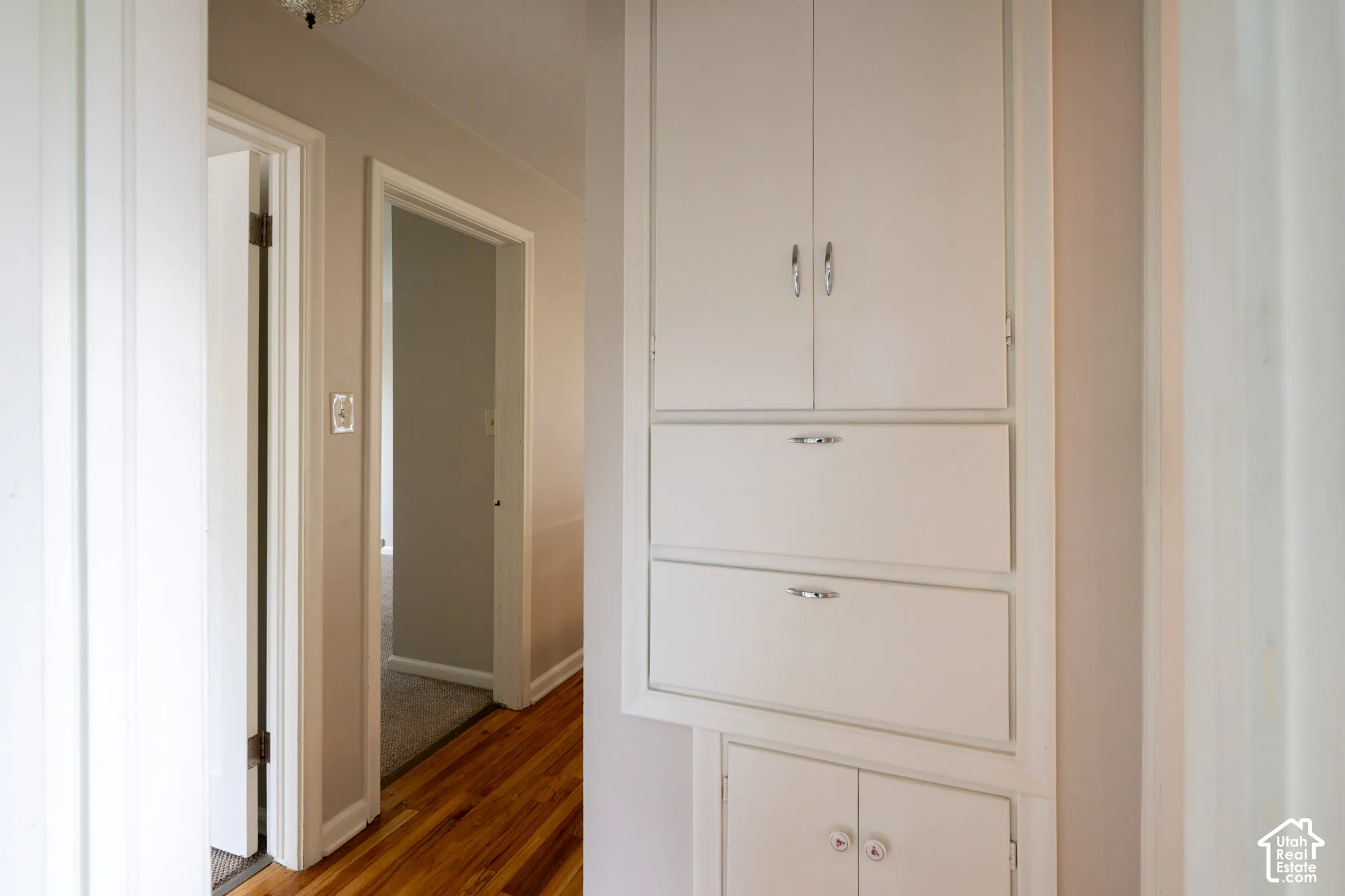 Built-in wall cabinetry featuring painted white finishes, metal hardware, and a combination of upper doors and drawers