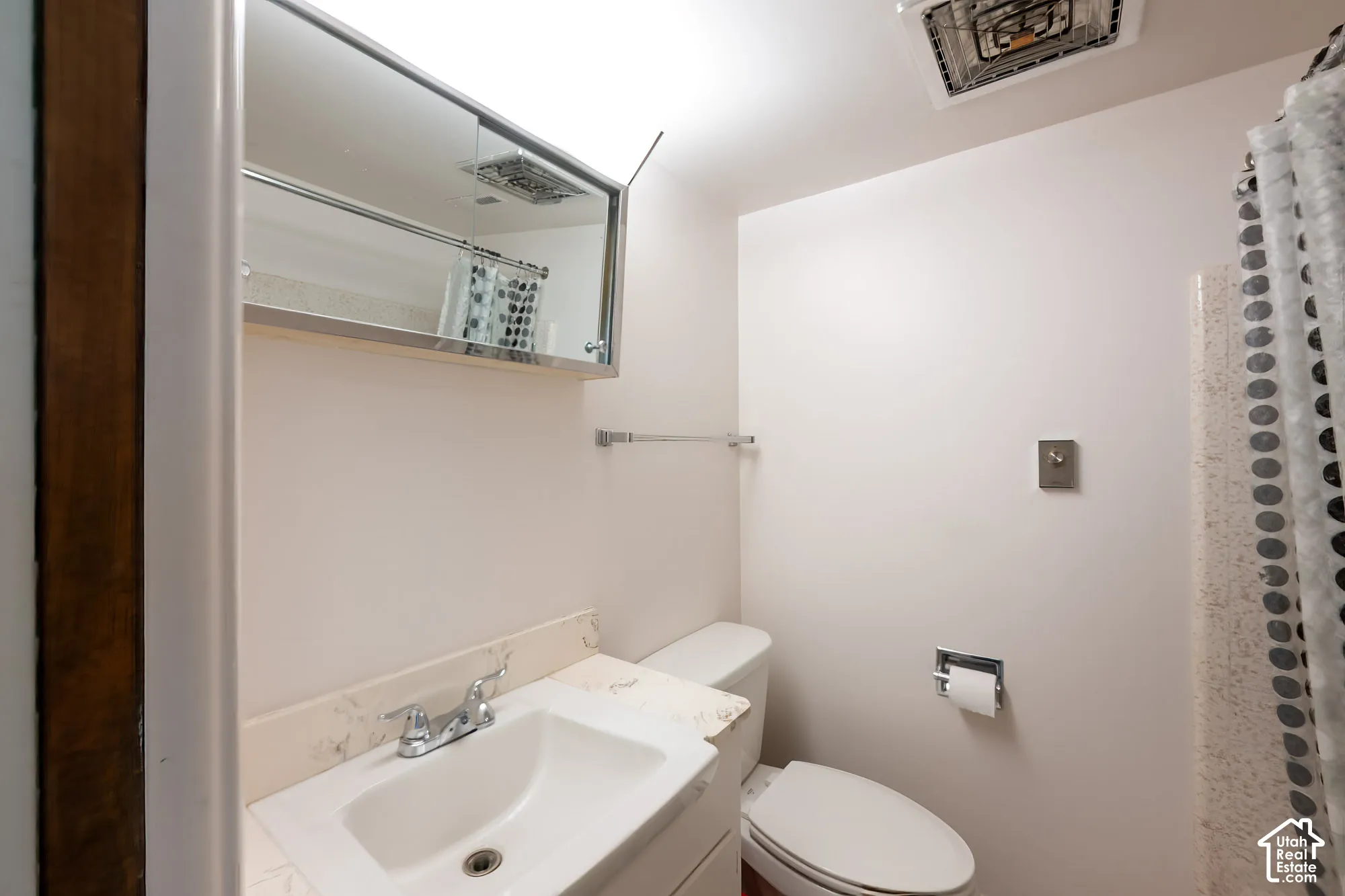 Bathroom featuring a vanity with an integrated basin, a mirrored medicine cabinet, a chrome faucet, and a wall-mounted towel bar