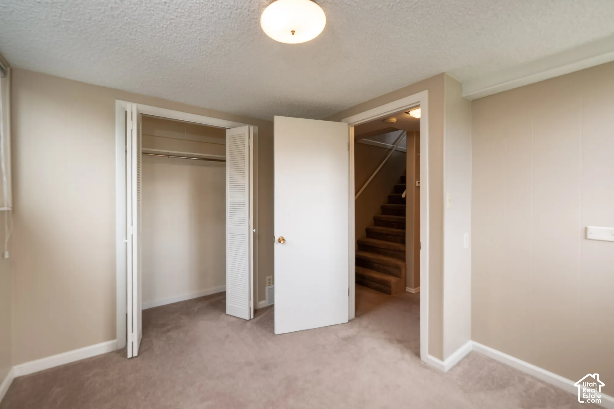 Neutral wall tones, carpeting, bi-fold closet doors, and flush-mount lighting