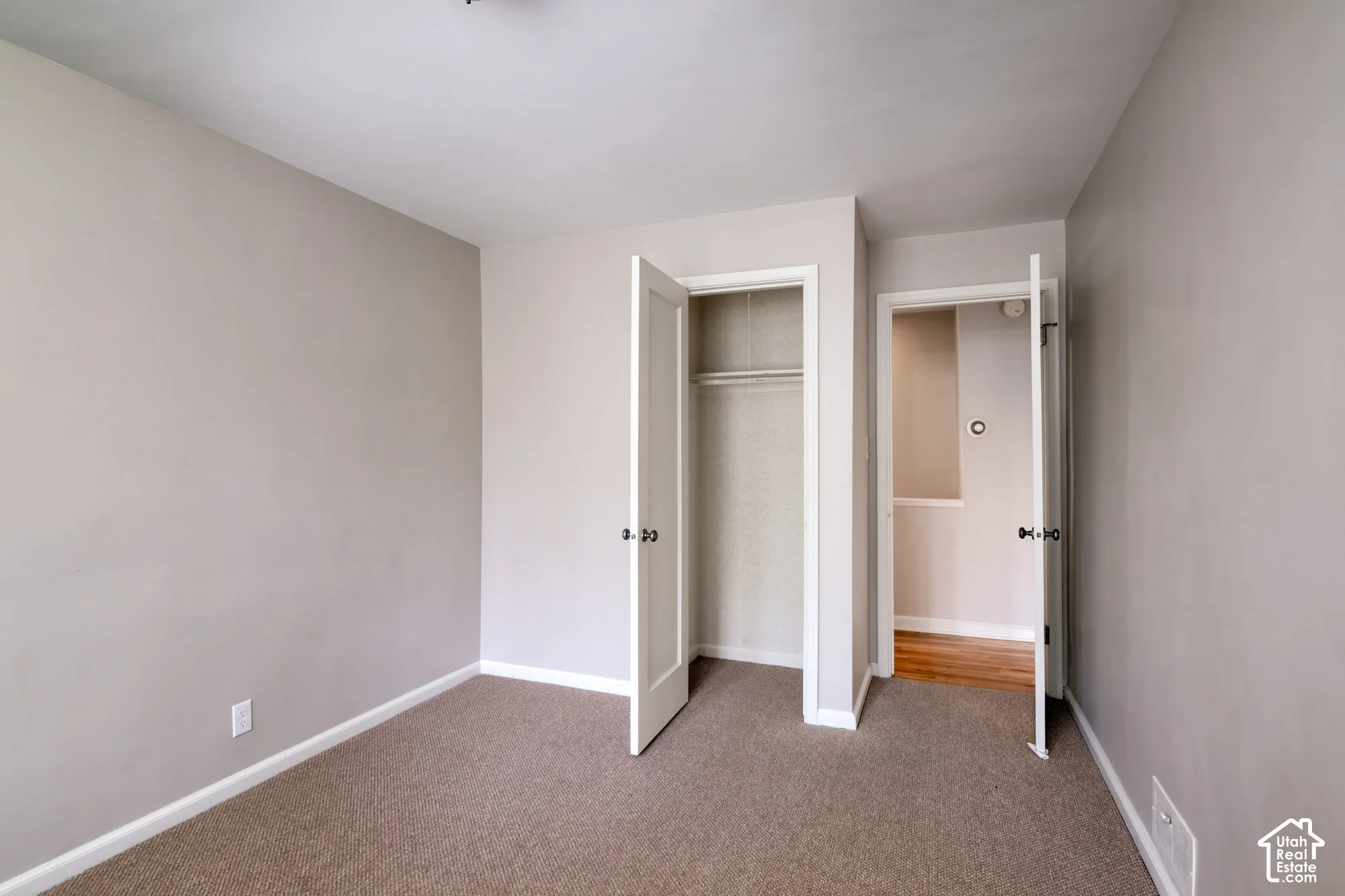 Neutral-toned interior room featuring wall-to-wall carpeting, an open-door closet, and solid core doors with round hardware