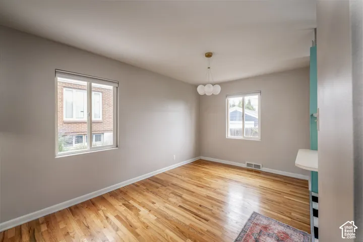Room featuring wood-finish flooring, dual windows with blinds, a multi-globe pendant light fixture, and built-in cabinetry