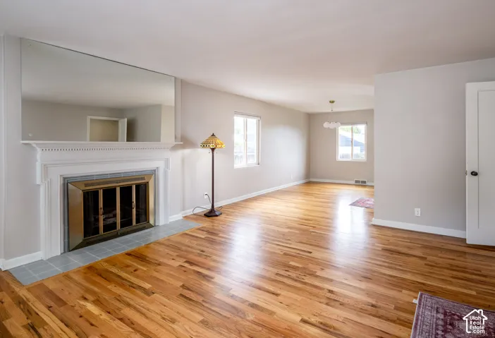 Living area featuring wood-finish flooring, a fireplace with a decorative mantel, an integrated wall mirror, and neutral wall tones