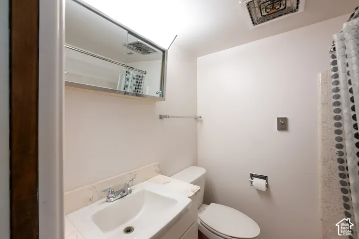 Bathroom featuring a vanity with an integrated basin, a mirrored medicine cabinet, a chrome faucet, and a wall-mounted towel bar