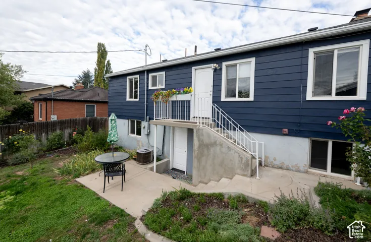 Exterior featuring blue lap siding, concrete patio, white metal railings, and dual entry points