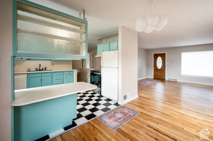 Kitchen featuring custom cabinetry, checkerboard tile flooring, built-in upper shelving with textured glass panels, and a peninsula counter