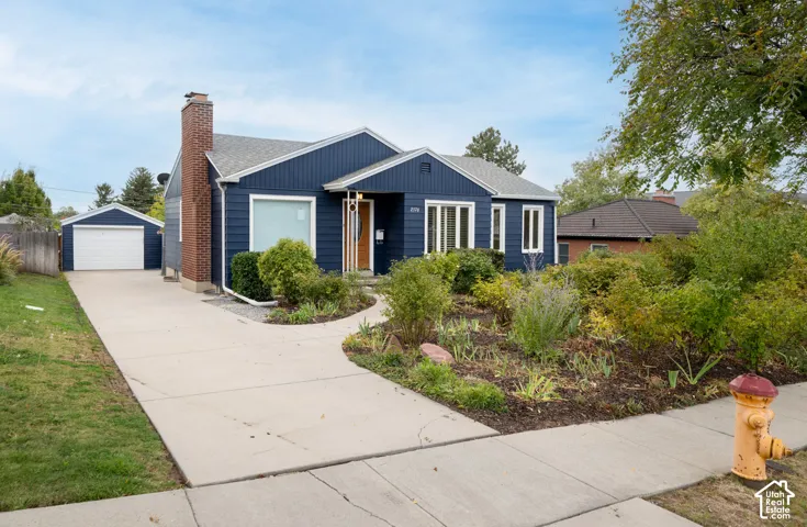 Exterior featuring dark blue horizontal siding, a prominent brick chimney, an attached garage, and a concrete driveway