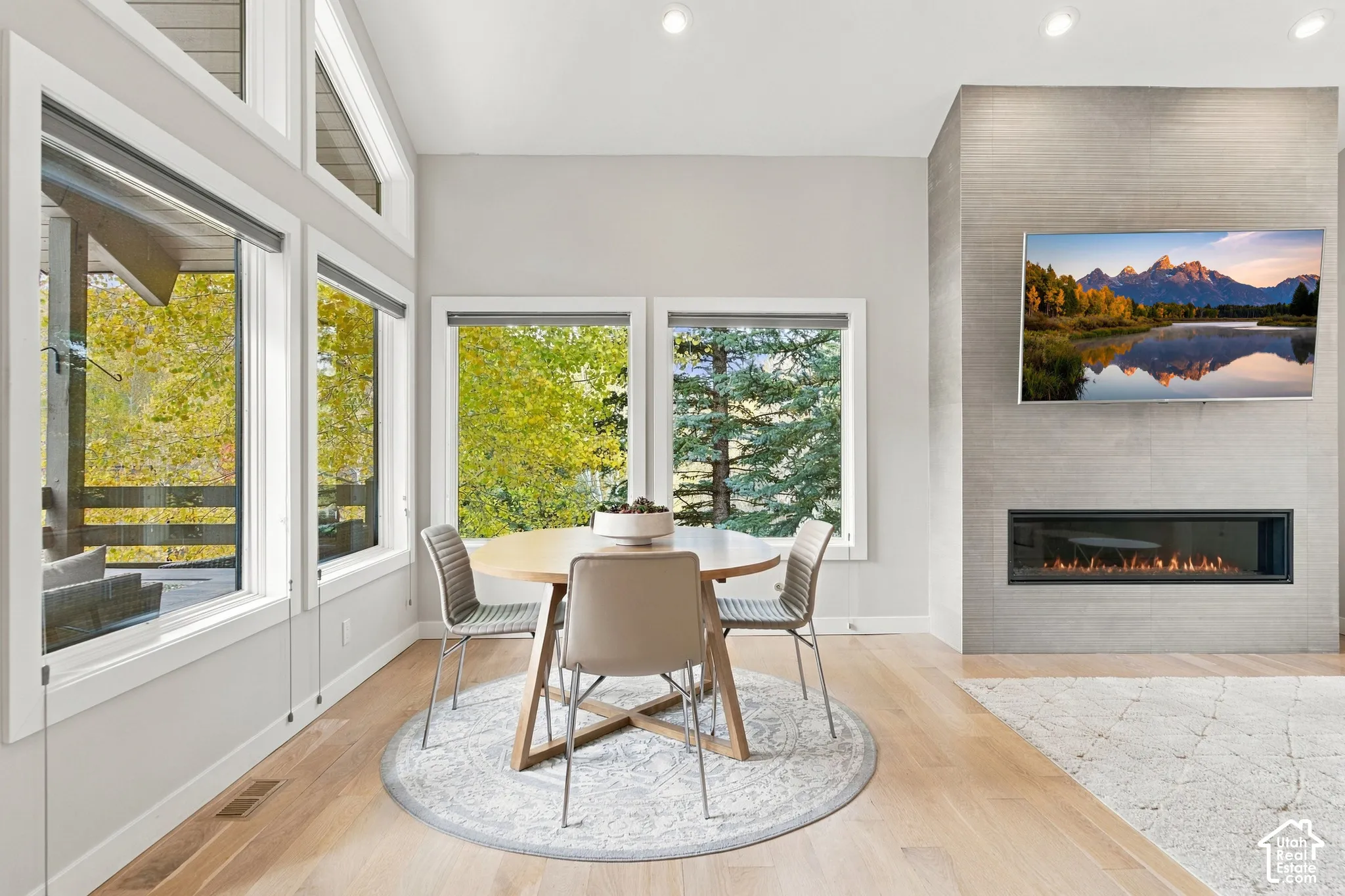 Vaulted ceilings with large windows, wood-finish flooring, and a floor-to-ceiling stone-tiled fireplace with a linear insert