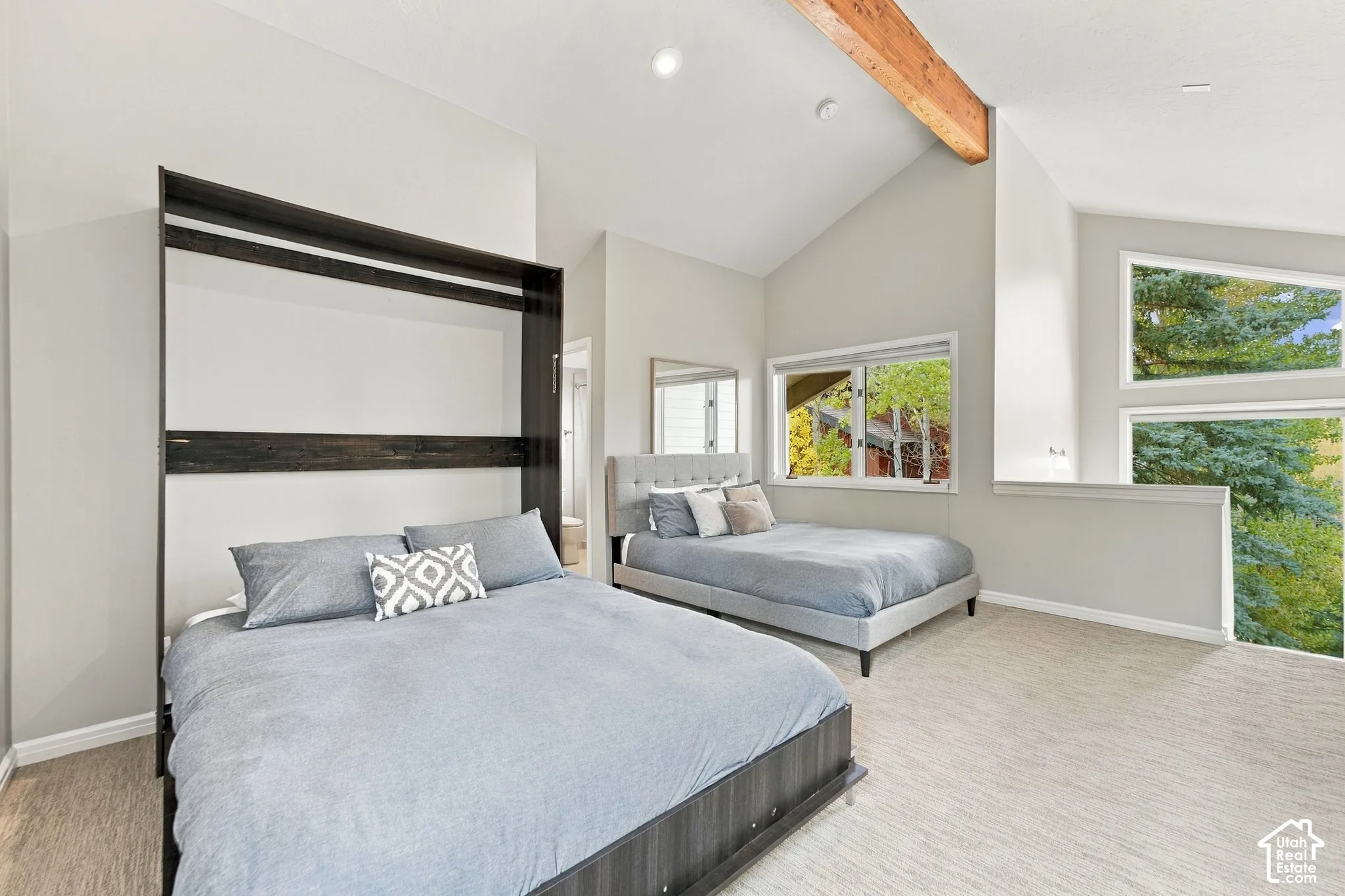 Vaulted ceilings featuring an exposed timber beam, multi-level windows, and integrated wall cabinetry