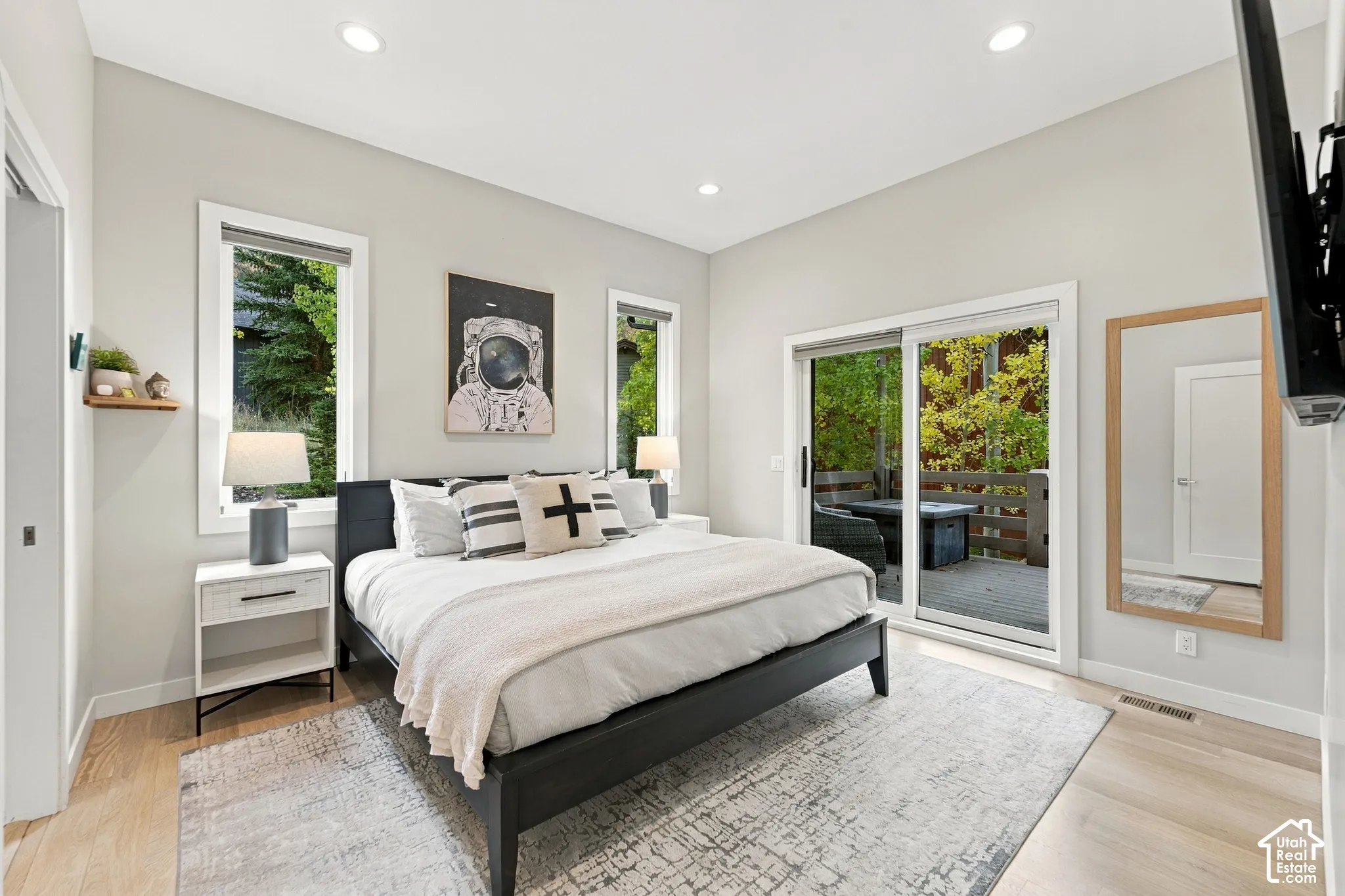 Room featuring neutral wall paint, recessed lighting, wood-finish flooring, two large windows, and a sliding glass door