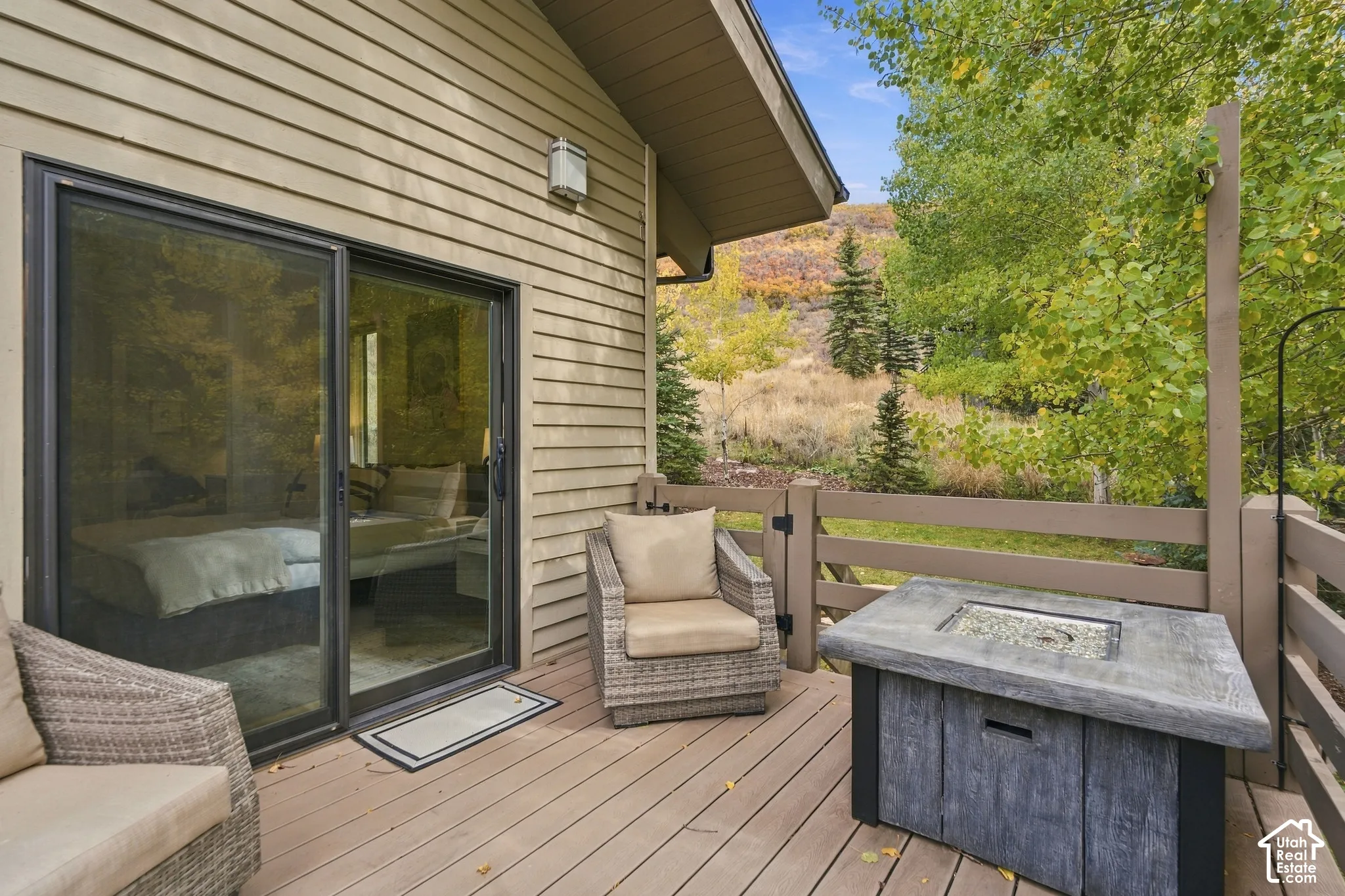 Composite decking, horizontal slat railing, sliding glass door, and exterior siding, accented by a square concrete fire table