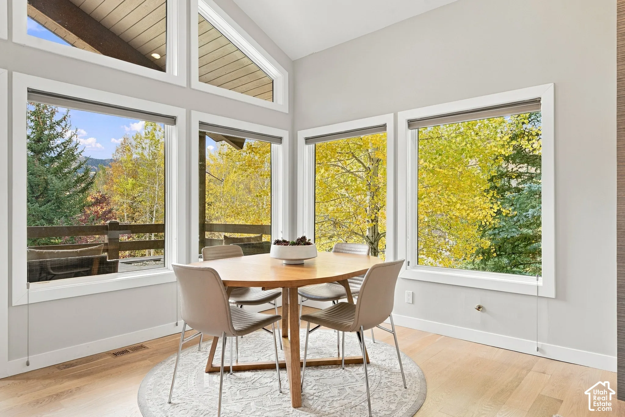 Vaulted ceilings with wood-plank detailing, floor-to-ceiling windows, wood-finish flooring, and natural exterior scenery