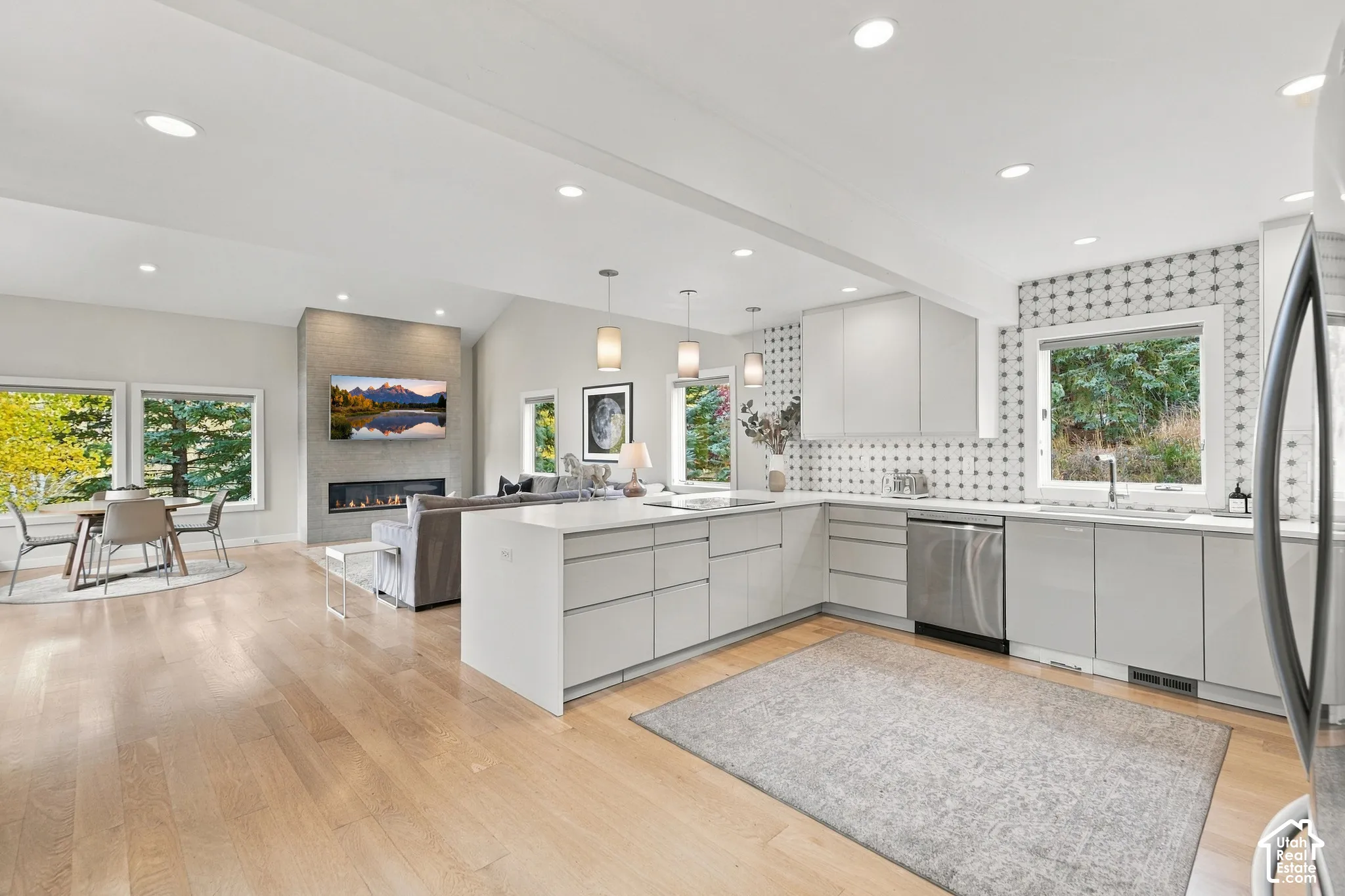 Kitchen featuring flat-panel cabinetry, quartz countertops, patterned tile backsplash, recessed lighting, and wood-finish flooring