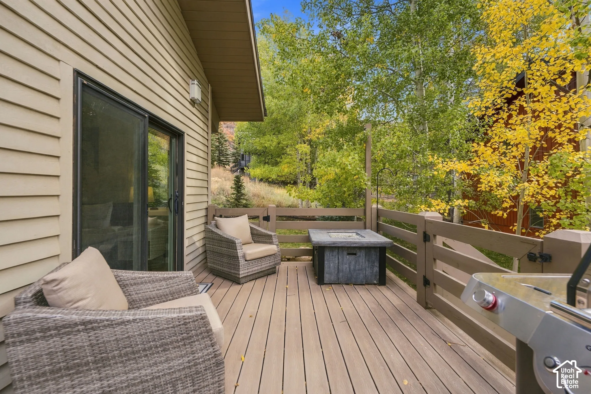 Exterior deck with horizontal wood-finish railing, sliding glass door, and vinyl siding
