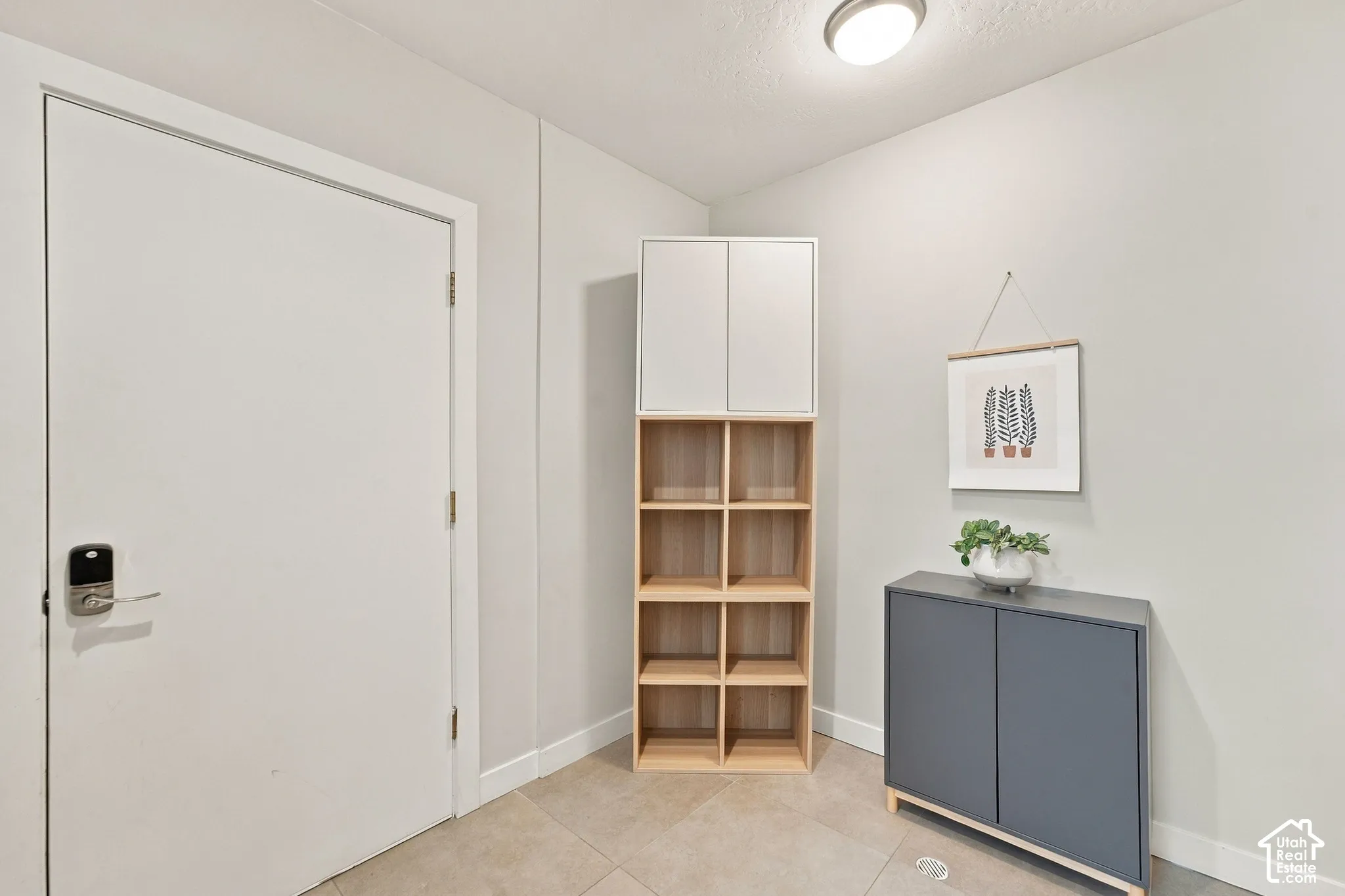 Solid-core door with electronic keypad entry hardware, flush-mount ceiling lighting, and neutral tile flooring