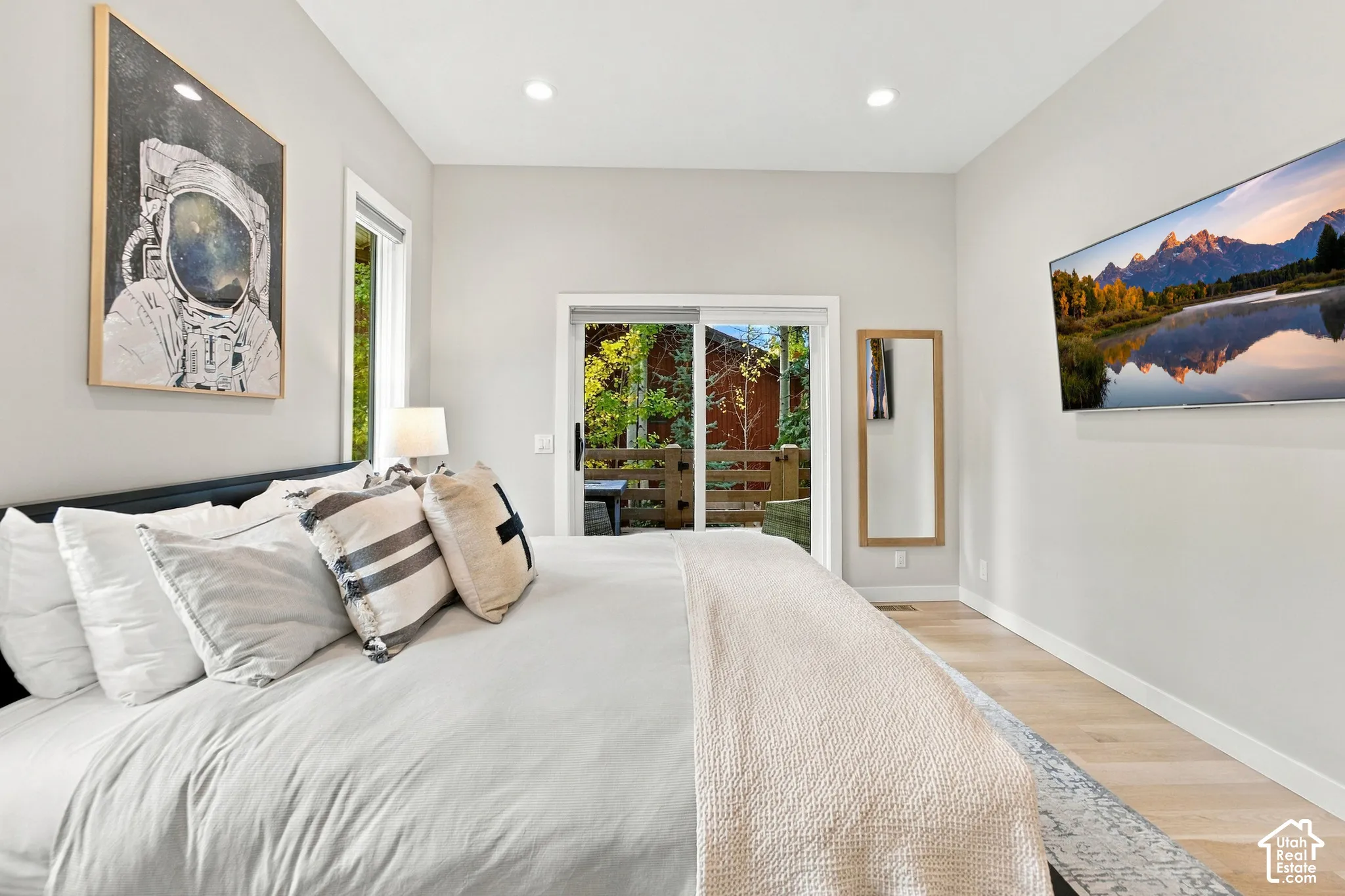 Light-toned wood-finish flooring, recessed lighting, and a white-framed sliding glass door providing exterior access