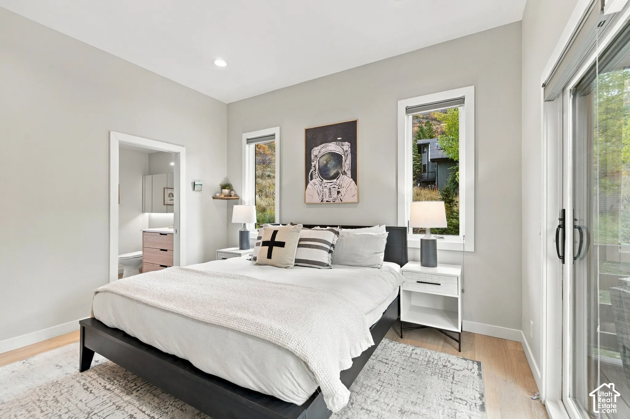 Light-filled room featuring wood-finish flooring, recessed lighting, dual windows, and a sliding glass door providing external access