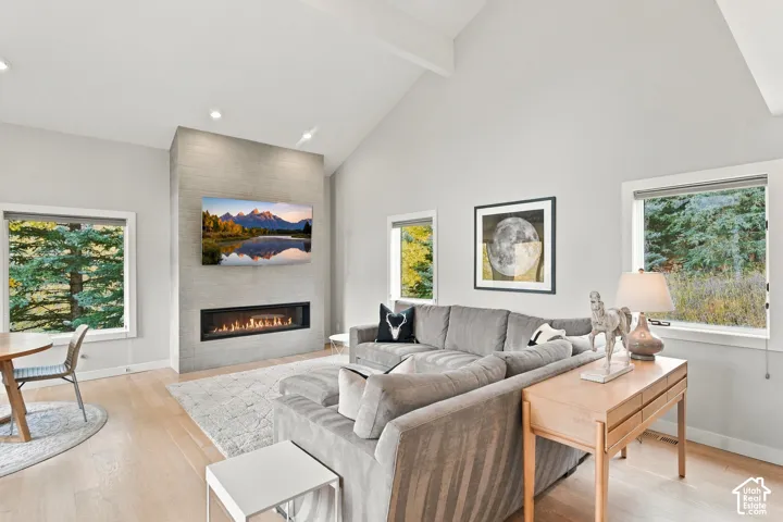 Vaulted ceilings, linear fireplace with a textured surround, recessed lighting, and expansive windows