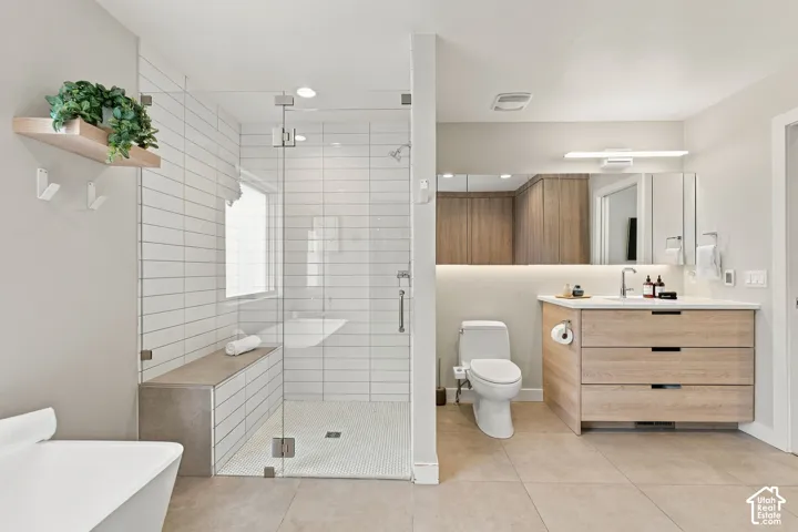 Bathroom featuring a glass-enclosed shower with horizontal wall tile and a built-in bench, a wood-finish vanity with a stone countertop, a full-width mirror with integrated lighting, and neutral floor tile