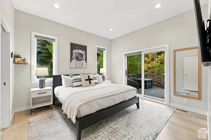 Room featuring neutral wall paint, recessed lighting, wood-finish flooring, two large windows, and a sliding glass door