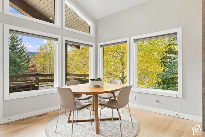 Vaulted ceilings with wood-plank detailing, floor-to-ceiling windows, wood-finish flooring, and natural exterior scenery
