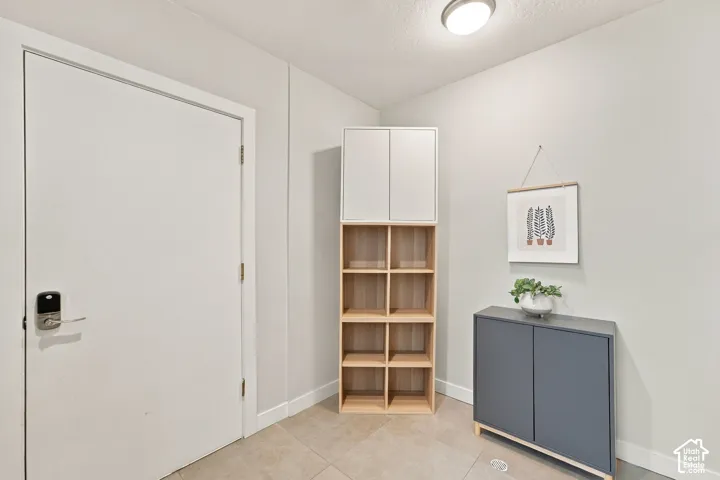 Solid-core door with electronic keypad entry hardware, flush-mount ceiling lighting, and neutral tile flooring
