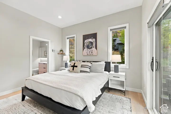 Light-filled room featuring wood-finish flooring, recessed lighting, dual windows, and a sliding glass door providing external access