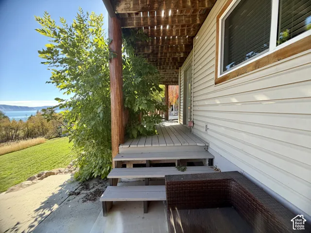 Covered wood deck featuring rustic timber support columns, horizontal siding, and concrete hardscaping
