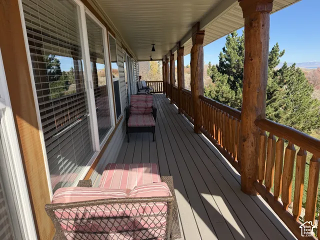 Covered exterior deck featuring exposed log structural posts, spindle railings, wood-finish decking, and multi-pane windows