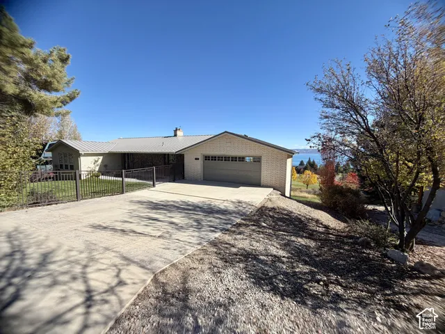 Single-story exterior with brick facade, metal roofing, attached multi-car garage, and concrete driveway