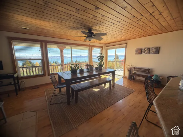 Natural wood-plank ceiling, wood-finish flooring, floor-to-ceiling windows, and a ceiling-mounted fan fixture