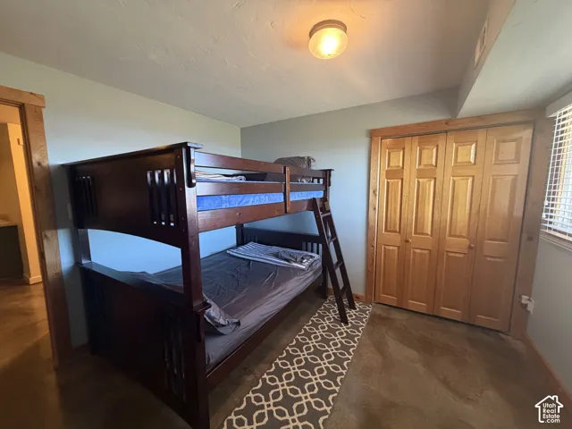 Room featuring concrete flooring, natural wood-finish door casings, bifold closet doors with raised panels, and a flush-mount circular ceiling fixture