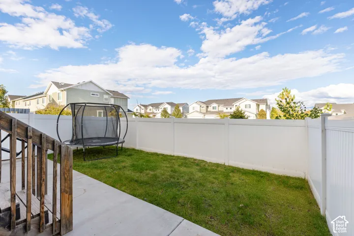 Private backyard featuring a concrete patio, green lawn, and white vinyl privacy fencing