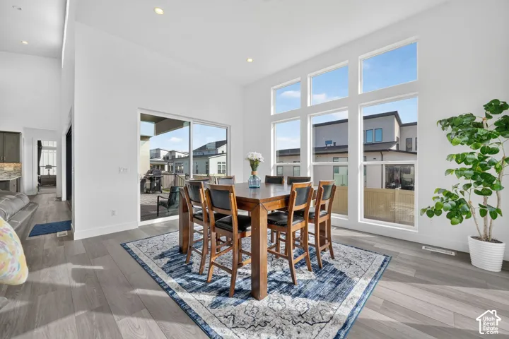 High-ceilinged room featuring expansive multi-pane windows, wood-finish flooring, recessed lighting, and a glass sliding door providing exterior access
