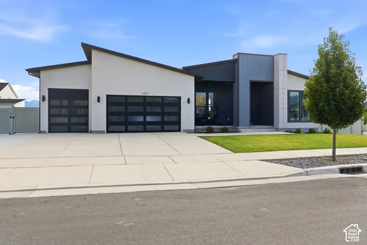 Modern exterior featuring an asymmetrical shed roofline, multi-textured facade with vertical siding, two glass-paneled garage doors, and a concrete driveway