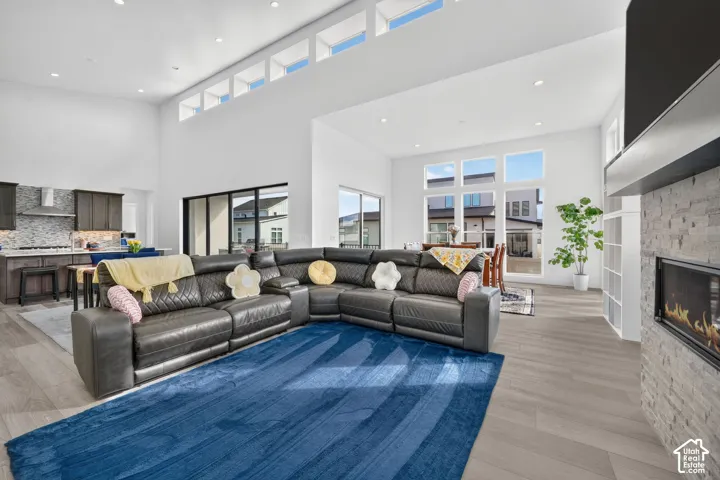 High ceilings with clerestory windows, stone-surround linear fireplace, wood-finish flooring, and recessed lighting