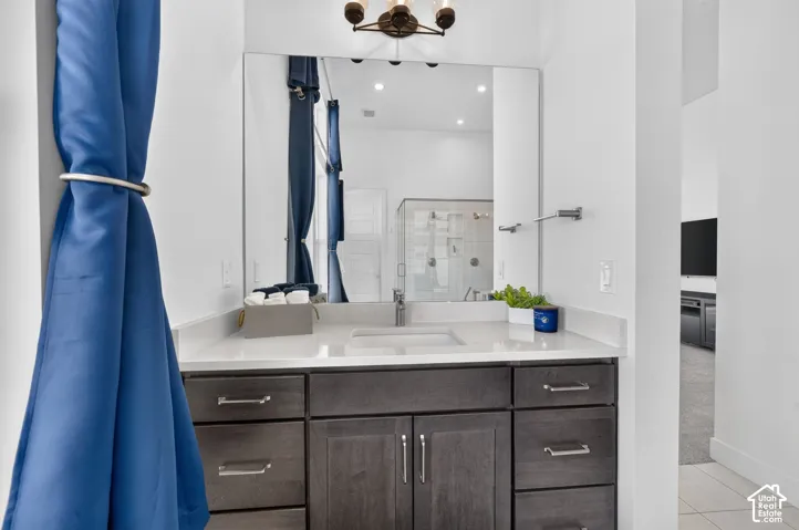 Vanity featuring dark wood-finish cabinetry, a rectangular undermount sink, a solid surface countertop, an oversized wall-mounted mirror, and a three-light fixture