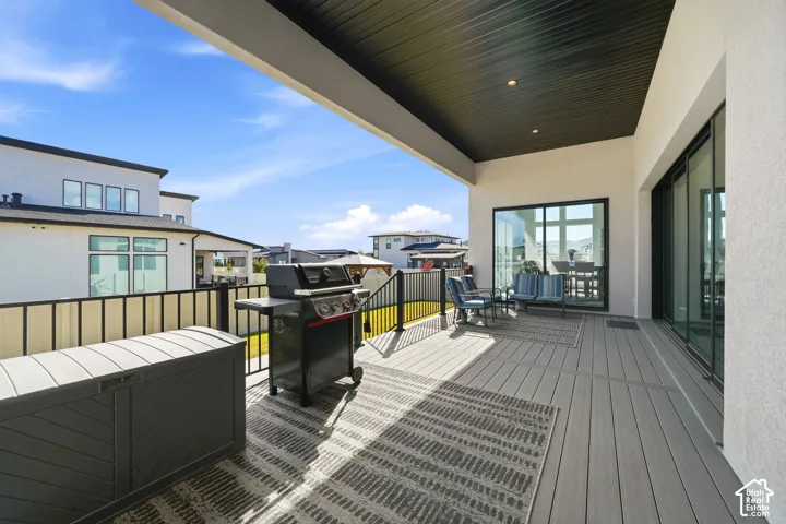 Covered exterior deck featuring composite decking, black metal railing, and recessed ceiling lighting