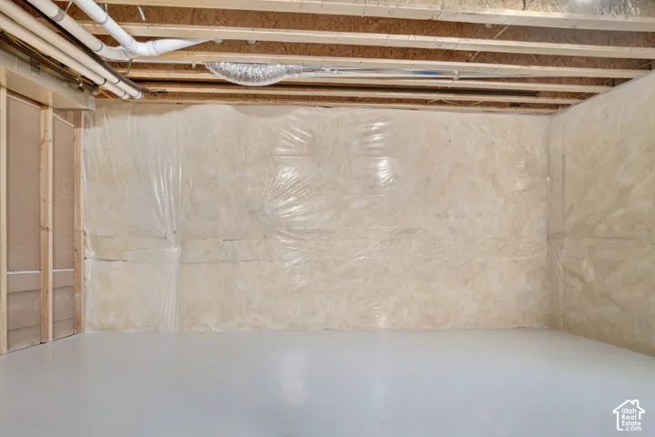 Unfinished space featuring concrete flooring, wood-stud framing, exposed joist ceiling, and vapor-barrier wall insulation