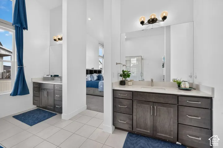 Dual vanities featuring dark wood-finish cabinetry, solid surface countertops, integrated sinks, large mirrors, and multi-bulb light fixtures