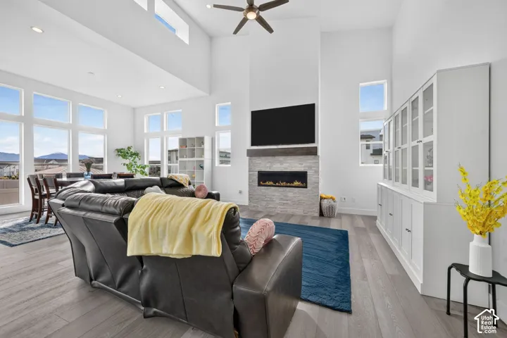 Vaulted ceilings, floor-to-ceiling stone-surround fireplace with linear insert, wood-finish flooring, built-in cabinetry, and expansive windows