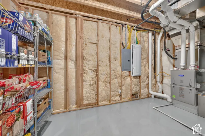 Unfinished storage space featuring exposed wall studs, batt insulation, a mounted electrical service panel, and a forced-air HVAC unit with overhead ductwork
